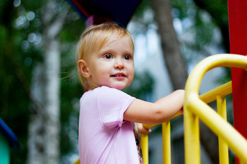 Wall Mural - Portrait of a pretty toddler girl playing on the playground on a beautiful summer day