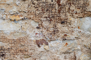 Wall Mural - Old wall with partially crumbling plaster with incoming supporting metal mesh