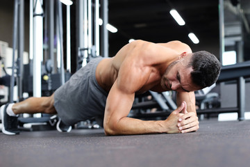 Portrait of a fitness man doing planking exercise in gym.