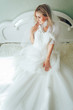 the bride sits on the bed and keeps the wedding dress in the hands
