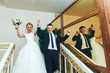 The bride and groom are happy when they leave the Church. Newlyweds come out of the Church with their hands in the air