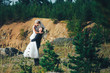 The bride and groom stand against the background of rocks at sunset. Newlyweds at sunset in a mountain forest