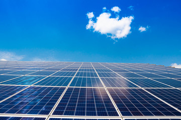 Solar panels for generating electricity against a blue sky with a white cloud. Alternative energy.