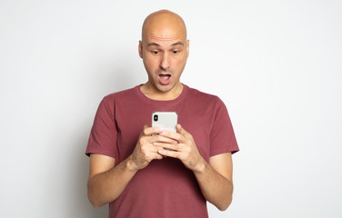 Wall Mural - Shocked bald man is reading unbelievable news on his smartphone