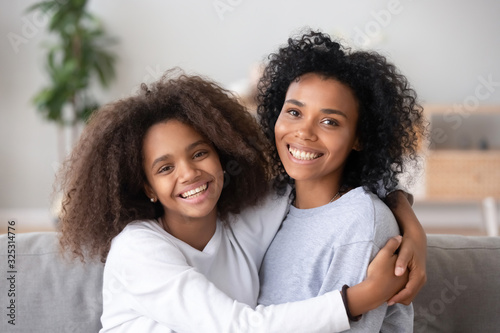 Fotomural Happy african mother and teen daughter embracing looking at camera