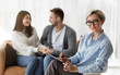 Family Psychologist Smiling While Couple Reconciling Sitting On Sofa Indoor