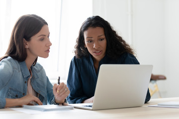 Focused successful mixed race female entrepreneurs discussing project.