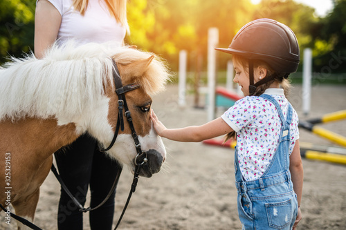 Cuadros en Lienzo Cute little girl and her older sister enjoying with pony horse outdoors at ranch