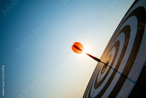 Fotografía Close up shot red darts arrows in the target center on dark blue sky background