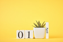 Wooden Blocks Calendar With Date 1st April And Plant On The Yellow Background. April Fools Day Concept
