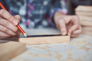 Wall Mural - Carpenter hands taking measurement with a pencil of wooden plank. Concept of DIY woodwork and furniture making