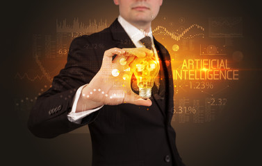 Businessman holding lightbulb with ARTIFICIAL INTELLIGENCE inscription, Business technology concept