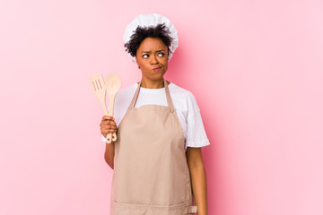 Wall Mural - Young african american cook woman confused, feels doubtful and unsure.