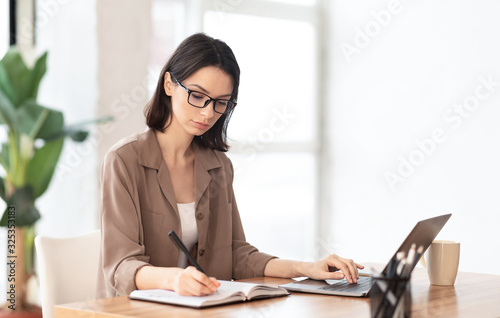 Fotomural Portrait of concentrated manager writing in notebook