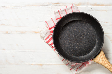 Frying pan or skillet on white wooden table.