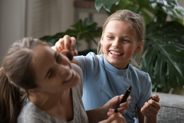 Close up overjoyed school age girl playing with decorative cosmetics.