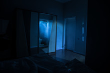 A Creepy Bedroom Scenery, Silhouette Of Scary Person Standing Reflected In Mirror With Mist And Toned Light.