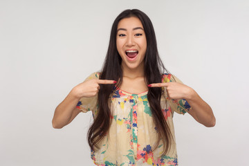 Wall Mural - Wow, I'm winner! Pretty asian girl with long hair in summer blouse pointing herself and looking at camera with excited amazed expression, boasting victory, proud of achievement. studio shot, isolated