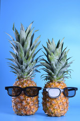 Pineapple in sunglasses close-up on blue background