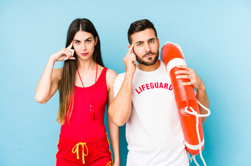 Wall Mural - Young lifeguard couple isolated pointing temple with finger, thinking, focused on a task.