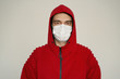 A man in a white medical mask in red clothes on a white background