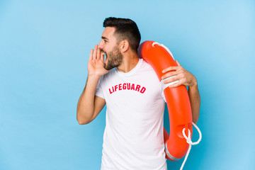 Wall Mural - Young handsome lifeguard man isoalted shouting and holding palm near opened mouth.