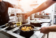 © romaset - Chef cooks fried potatoes with pieces of meat in a restaurant kitchen