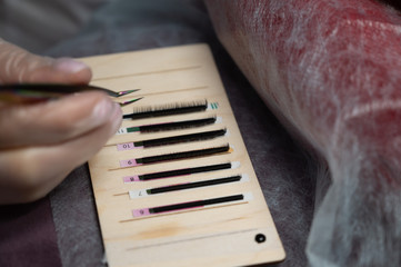 Closeup of the hand of a craftsman with tweezers. A set of materials for eyelash extensions.