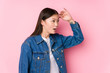 © Asier - Young chinese woman posing in a pink background isolated looking far away keeping hand on forehead.