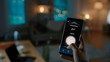 © Gorodenkoff - Close Up Shot of a Smartphone with Active Smart Home Application. Person is Tapping the Screen To Turn Lights On/Off in the Room. It's Cozy Evening in the Apartment.