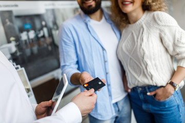 Wall Mural - Close up photo, sale, consumerism, shopping and people concept - happy couple with credit card at decoration store in mall