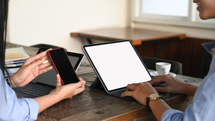 Leinwandbilder - A woman showing black blank screen smartphone to A man who typing on white screen tablet. Collaboration concept.
