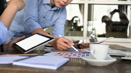 Leinwandbilder - Cropped image of graphic designer discussing at the wooden meeting table with working stuff.