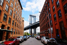 Manhattan Bridge Seen From A Red Brick Buildings In Brooklyn Street In Perspective, New York, USA. Beautiful Classic Apartments In New York City. Beautiful American Street. Famous View.