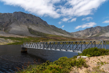 Buffels River, Western Cape, South Africa. Dec 2019. Buffels River Dam, metal walkway across the reservoir and the Hottentots Holland mountains background near Rooiels, Western Cape.