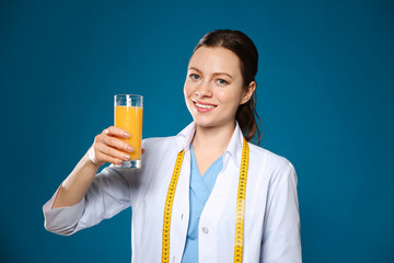 Poster - Nutritionist with glass of juice on blue background