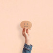 © oatawa - Hand holding happy face smiling comment in speech bubble on pastel background.