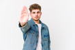 © Asier - Young blond curly hair caucasian man isolated standing with outstretched hand showing stop sign, preventing you.