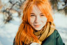 Portraits Of A Charming Red-haired Girl With A Cute Face. Girl Posing On Camera In The City Center In Winter. She Has A Wonderful Mood And A Lovely Smile