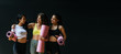 © Vittaya_25 - Panoramic banner. group of sporty multicultural women slim body smiling holding yoga mat at dark black wall background in fitness gym resting after yoga class, sport, yoga training, lifestyle concept