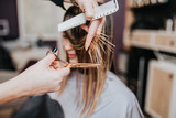 Beautiful young woman getting her haircut by a hairstylist at a beauty salon.