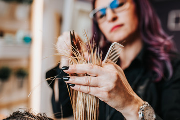 Beautiful young woman getting her haircut by a hairstylist at a beauty salon.