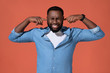 © Romario Ien - Man plugs his ears with hands for not hear anymore. Photo of african man in casual outfit on coral background.