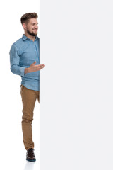 Wall Mural - Happy casual man smiling and presenting an emplty billboard