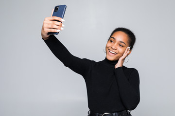 Wall Mural - Latin girl waving on the smart phone while during a video call isolated on a gray background