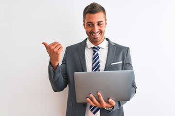 Canvas Print - Young handsome business man working using computer laptop over isolated background pointing and showing with thumb up to the side with happy face smiling