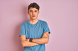 © Krakenimages.com - Teenager boy wearing casual t-shirt standing over blue isolated background skeptic and nervous, disapproving expression on face with crossed arms. Negative person.