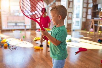 Adorable toddlers playing around lots of toys at kindergarten