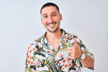 Sticker - Young handsome man wearing Hawaiian summer shirt over isolated background doing happy thumbs up gesture with hand. Approving expression looking at the camera with showing success.