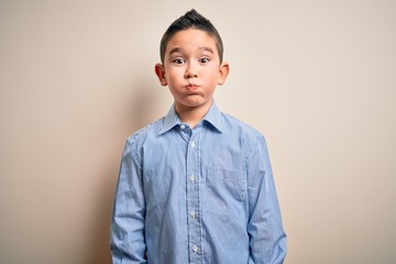 Sticker - Young little boy kid wearing elegant shirt standing over isolated background puffing cheeks with funny face. Mouth inflated with air, crazy expression.